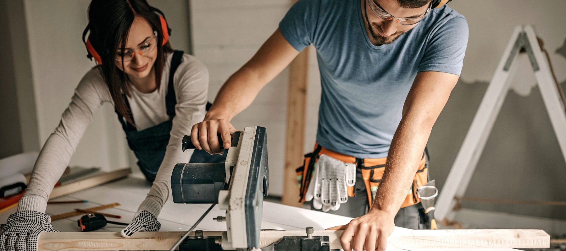 Couple using a chop saw in their garage